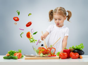 Petite fille coupant des légumes